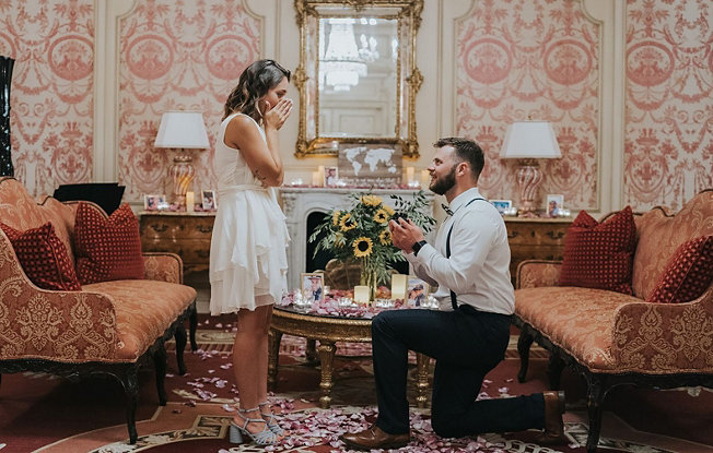 Bearded man proposing to woman in dress with a diamond engagement ring