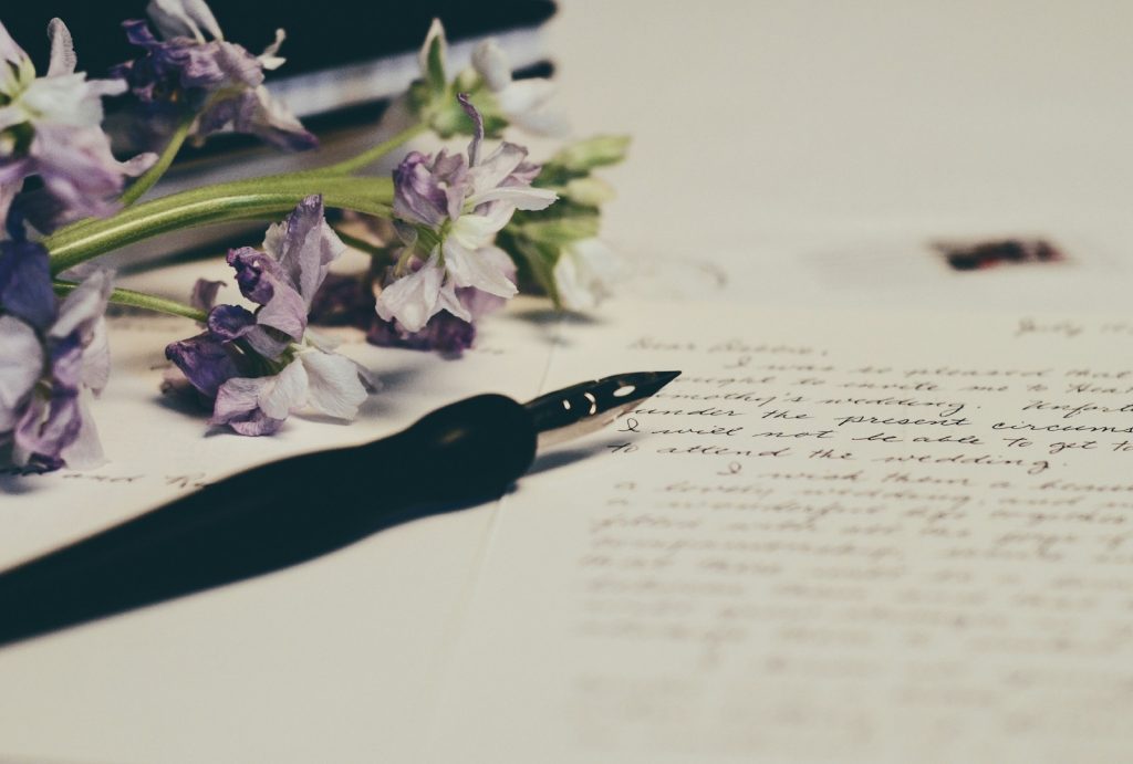 Photo of handwritten wedding vows with fountain pen and flowers on the page. 