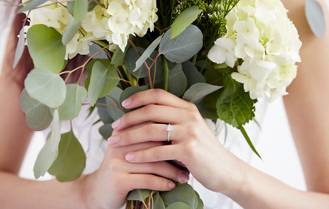 A bride holding a bouquet of flowers wearing a diamond engagement ring