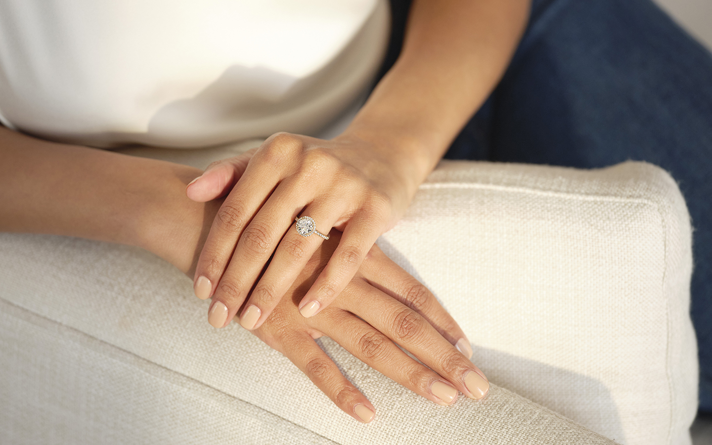 Photo of woman’s hands, she is wearing a warm diamond engagement ring. 