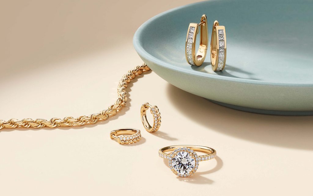 Yellow gold jewelry with diamonds including earrings and a halo ring.
