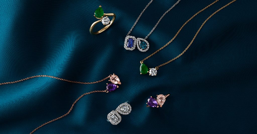 Three two-stone gold necklaces and three-two stone gold rings with diamonds and gemstones in yellow, white and rose gold.
