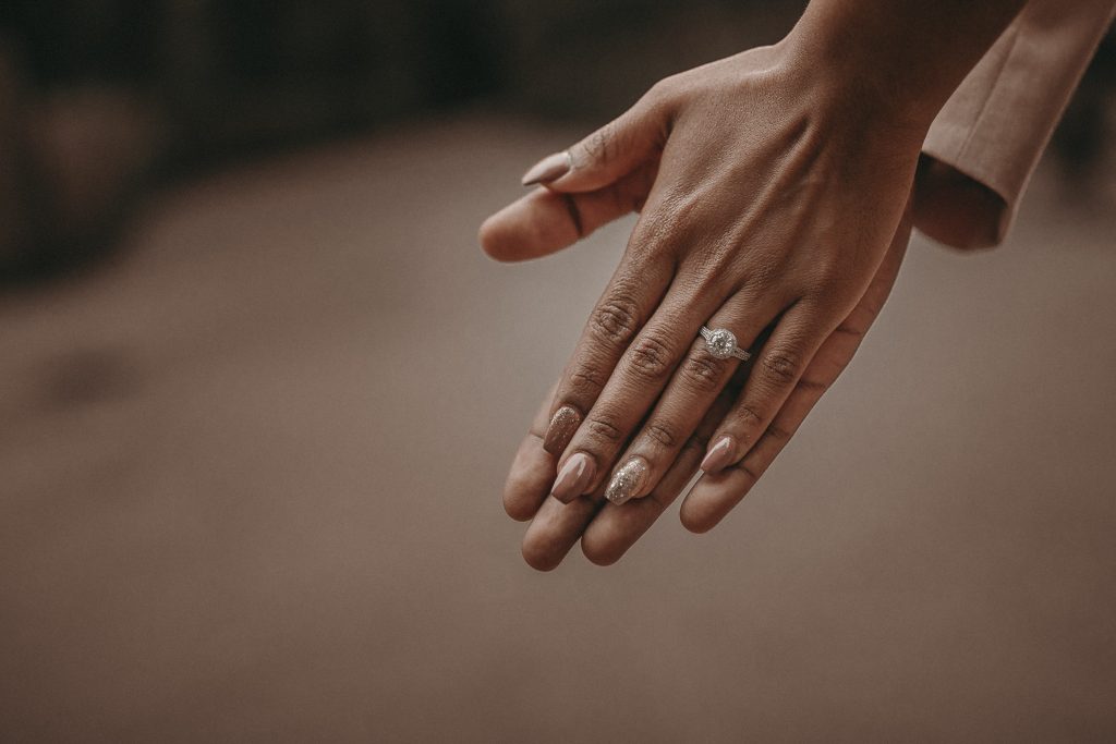 Photo of a bride’s hand pressed up on her groom’s hand.