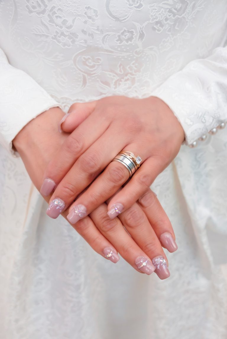 Photo of a bride’s hands, she has nails with crystals.