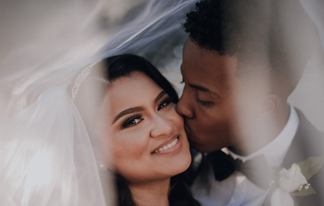 A groom kissing a bride on the cheek