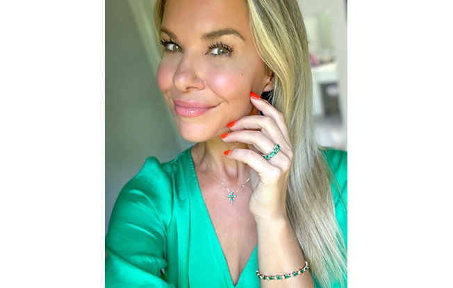 Blonde woman showing off her green diamond jewelry