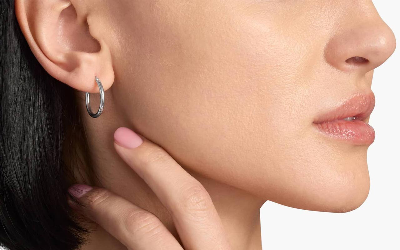 Close-up profile of a person wearing platinum hoop earrings