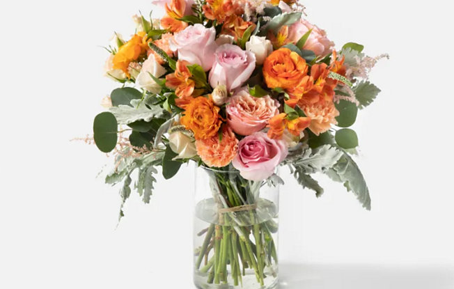 A glass vase with orange, pink and white flowers from Urban Stems