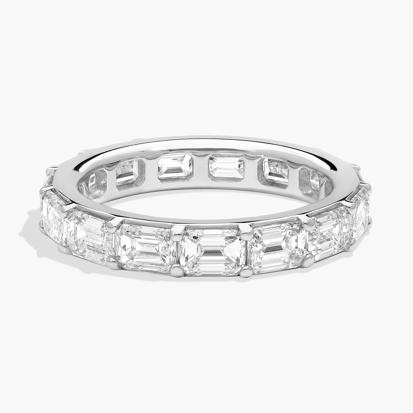Side view of an east-west emerald cut diamond eternity ring in platinum