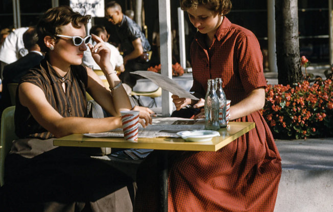 Two women wearing vintage clothing sitting together outdoors at a restaurant
