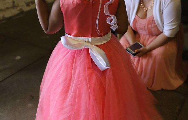 A little girl in a bright pink dress with a white bow