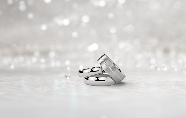 Three white gold men's engagement rings on a sparkling white background