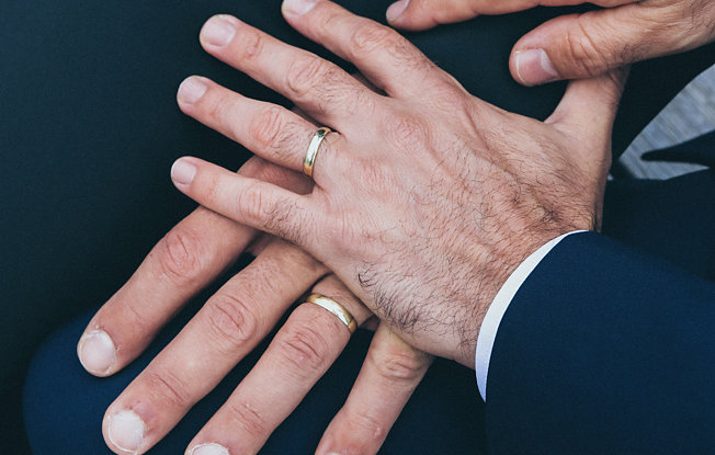 Two men's hands wearing gold engagement rings