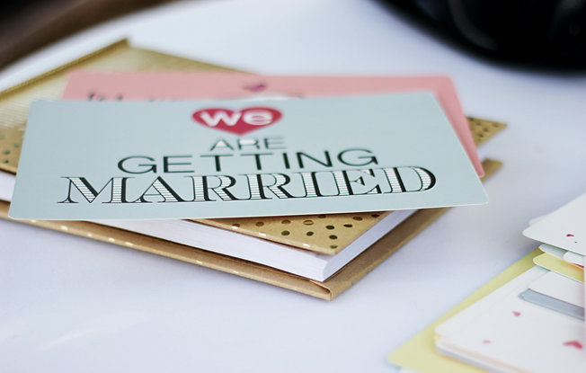 A Wedding invitation sitting on top of a notebook on a table