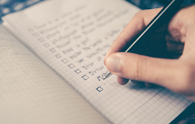 A person writing a to do list in a notebook
