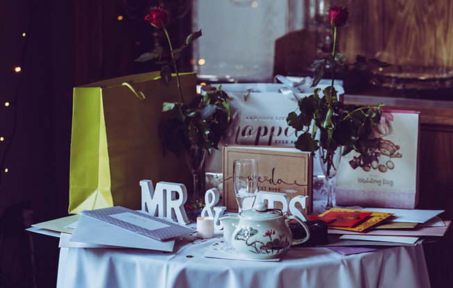 Wedding gifts in different sized bags sit on a table dressed with a white table clothes and a Mr. and Mrs. sign