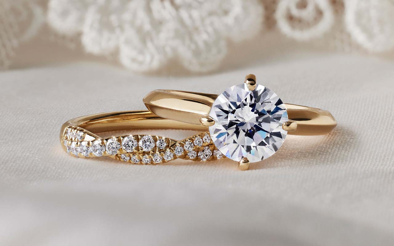 Two gold diamond rings lying on a white cloth