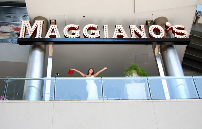 A woman in a wedding dress stands under the Maggiano’s sign in Las Vegas