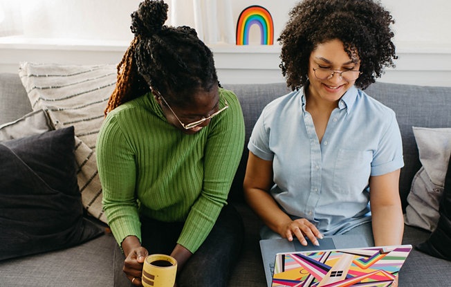 Two women smiling at a laptop together.