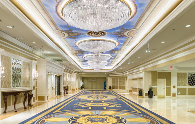 An interior hallway of the Westgate Resort Las Vegas adorned with a patterned rug and chandeliers