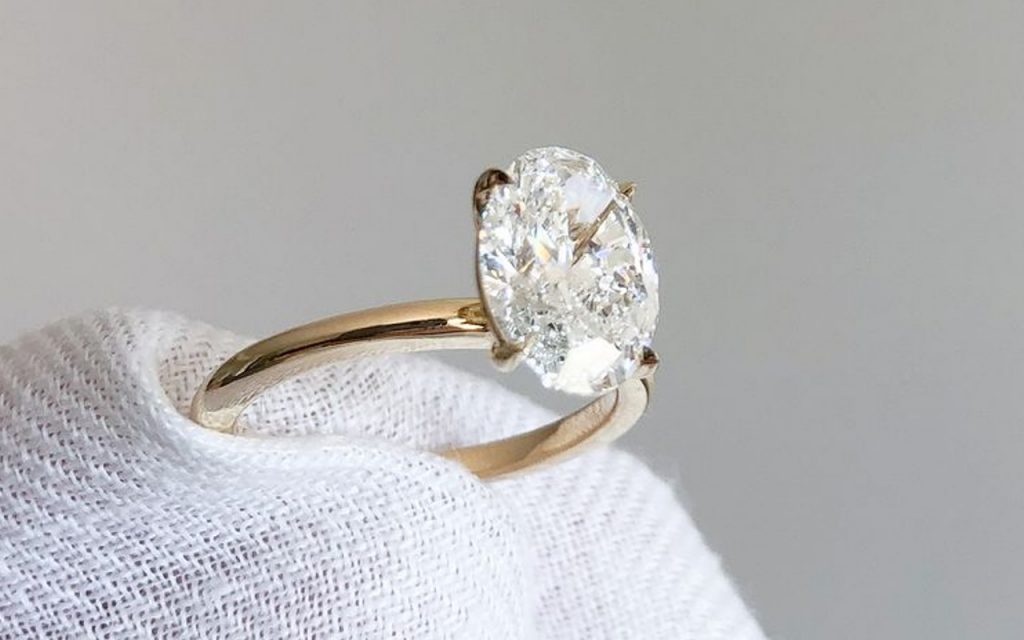 Close up of a person holding a diamond ring with a white cloth
