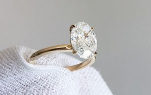 Close up of a person holding a diamond ring with a white cloth