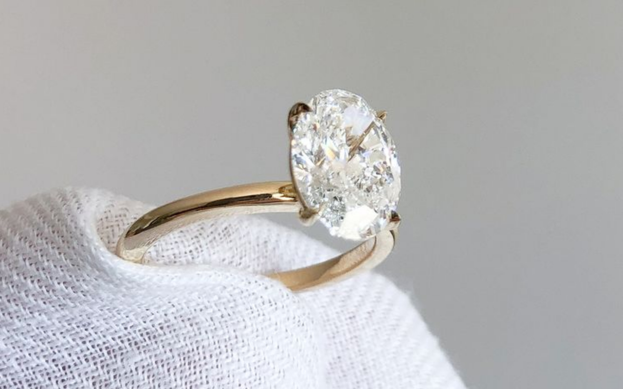 Close up of a person holding a diamond ring with a white cloth